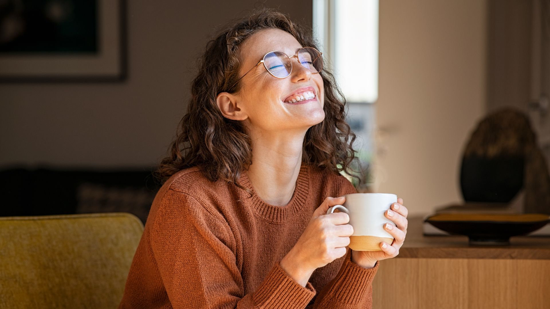 A woman sitting quietly at home, enjoying a warm drink.